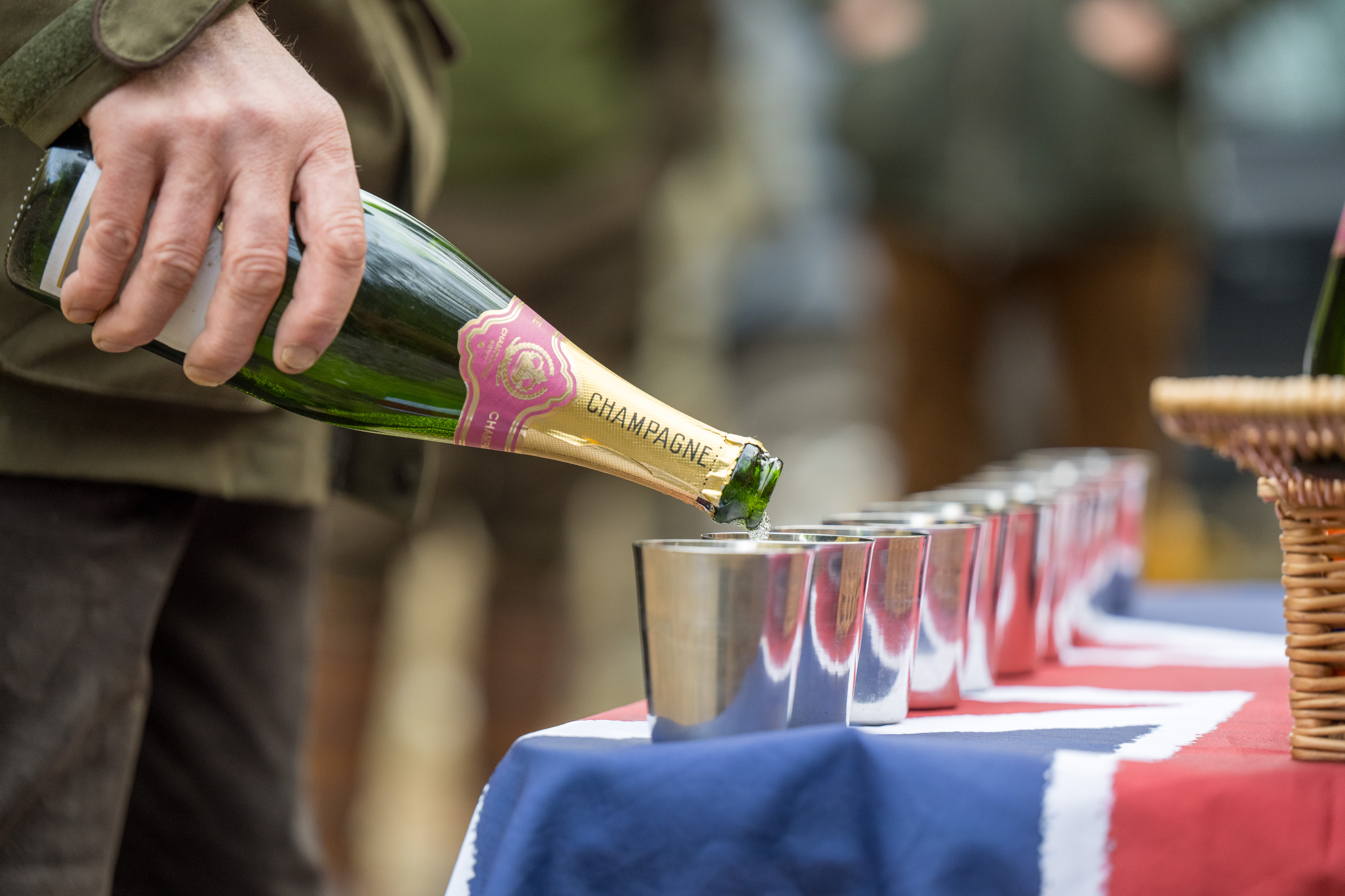 Champagne being poured into silver cups at a shoot-day drinks table